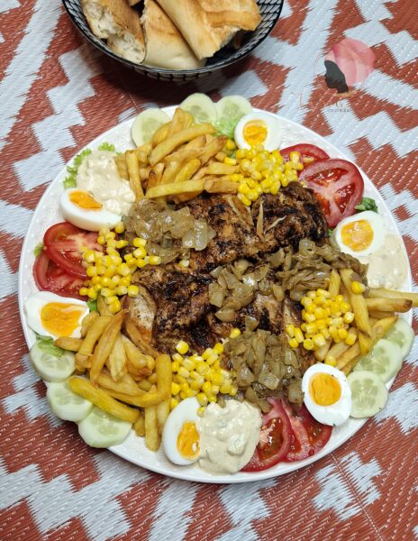 Salade westaf avec du poulet, sauce oignons, crudités présentée dans un grand plat 