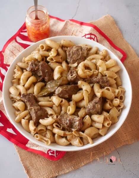 Assiette de macaroni à la viande préparée à la sénégalaise, avec sauce tomate et morceaux de viande.
